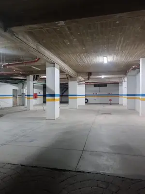 an empty parking lot with white columns in a parking garage at Appartement hay mohammadi GH26 in Oulad Akkou