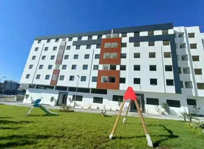 a large building with two playground equipment in front of it at شقة مريحه in Oulad Akkou