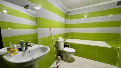 a green and white bathroom with a sink and a toilet at Diamond Fes Apartment in Fès
