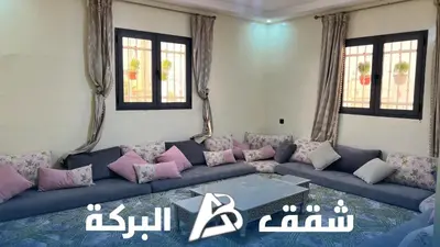 a living room with a blue couch with pink pillows at Appartements Al Baraka in Oulad Akkou