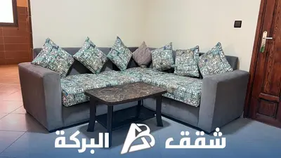 a couch with pillows and a table in a room at Appartements Al Baraka in Oulad Akkou