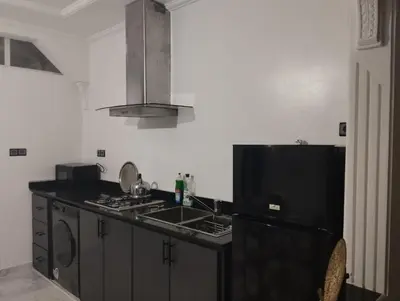 a kitchen with a black refrigerator and a sink at Super appartement quartier paisible proches toutes commodités in Azrou