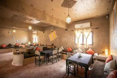 a living room with tables and chairs and a bar at Hotel Dar Sahara in Merzouga