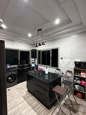 a kitchen with a black counter and chairs in it at Villa avec piscine in Meknès