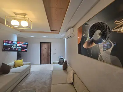 a living room with a couch and a painting on the wall at Appartement luxueux in Ifrane