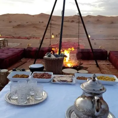 a table with food on it in the desert at TRIP Merzouga luxury camp in Hassilabied