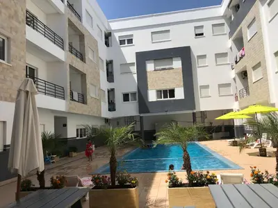 an apartment building with a swimming pool in a courtyard at Spacious Apartment PoolAir Conditioning Terrace in Oulad Akkou