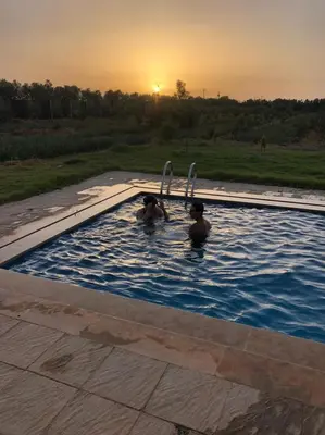 two people in a swimming pool at sunset at Villa Adam in Meknès