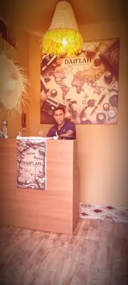 a man standing behind a counter with a sign at Chambre partagée Hostel DAIFLAH