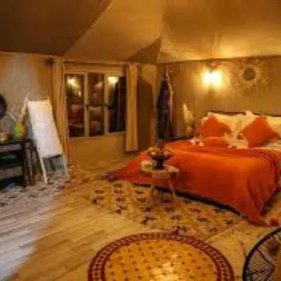 a bedroom with a bed with orange sheets and a rug at Merzouga tente luxury in Merzouga