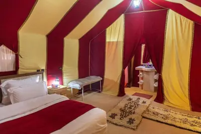 a bedroom with a tent with a bed and a bench at Fatima Luxury desert camp in Merzouga
