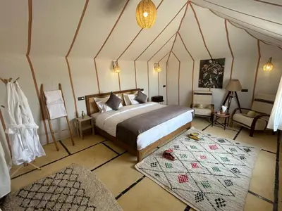a bedroom with a bed and a chair in a room at Aurora Dunes Camp in Merzouga