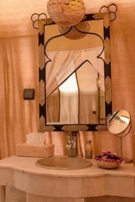 a bathroom with a sink with a large mirror at Sand Fish Camp in Merzouga