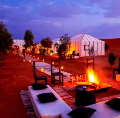 a group of tables and chairs next to a tent at Sud Est Camp in Merzouga