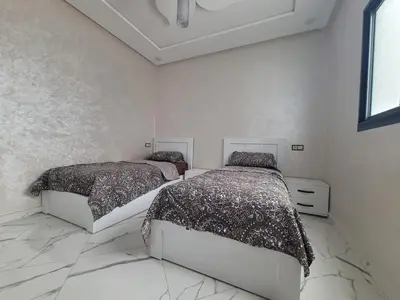 two beds in a bedroom with white walls and marble floors at Bella Nova Air-Conditioned Apartment in Azrou