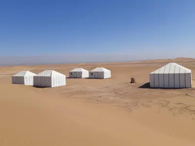 a group of white buildings in the desert at Starlit Desert Camp in Foum Zguid