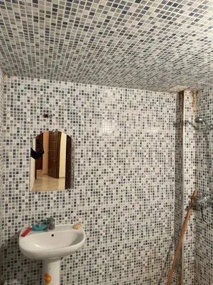 a bathroom with a sink and a mirror on a tiled wall at Belle appartement et spacieuse in Meknès