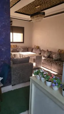 a living room with couches and flowers on a table at Belle appartement in Meknès