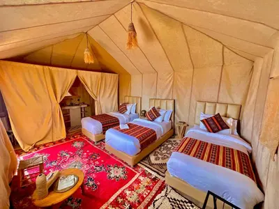 a group of four beds in a tent at Sandside Luxury Camp in Merzouga