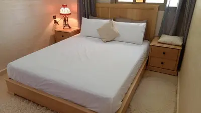 a bedroom with a large white bed with two night stands at appartement lamia in Azrou
