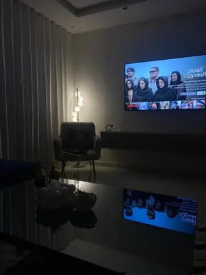 a living room with a flat screen tv and a chair at شقة فخمة وهادئة in Ifrane