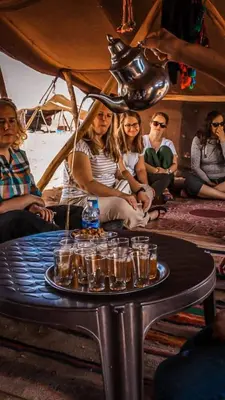 a group of people sitting around a table with glasses on it at Sahara serenity camp in Merzouga