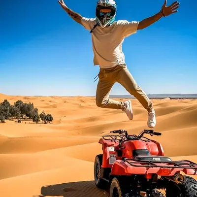 a man jumping over a quad bike in the desert at Merzouga Toop Luxury Camp in Merzouga