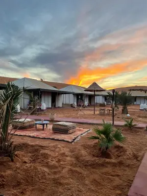 a building in the desert with a sunset in the background at Merzouga in Merdani