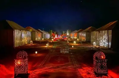 a parking lot with lit up huts at night at مرزوكة in Merzouga