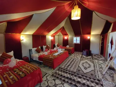 a room with two beds and a red and white ceiling at Starvile Luxury Camp in Merzouga