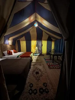 a room with a tent with a bed and a table at Ksar merzouga luxury camp in Merzouga