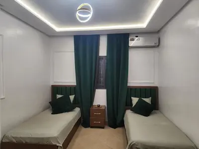 two beds in a room with green curtains at Villa Luxe Fès avec Piscine & Spa, proche aéroport, Private Hammam in Fès