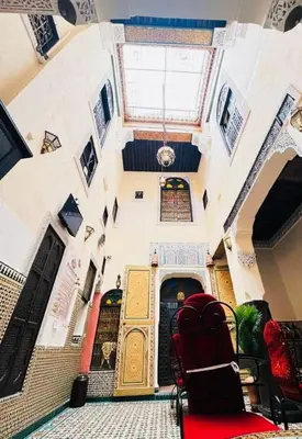 a room with a red chair in front of a building at Riad Panoramik in Fès
