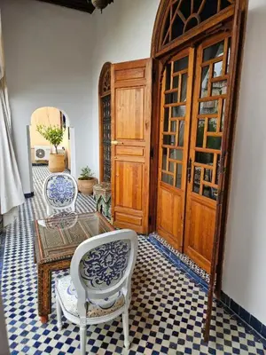 a room with a table and chairs and a door at Chambre topaze - Riad lotus bleu in Fès