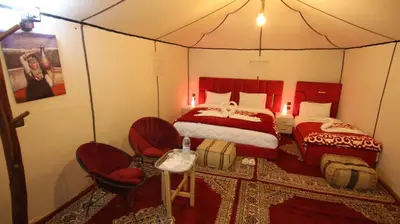 a bedroom with two beds and two chairs in a tent at Tenere Luxury Camp in Merzouga