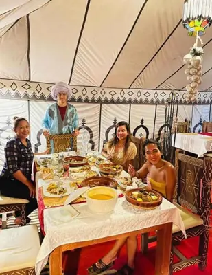 a group of people sitting around a table in a tent at Itran luxury camp in Merzouga