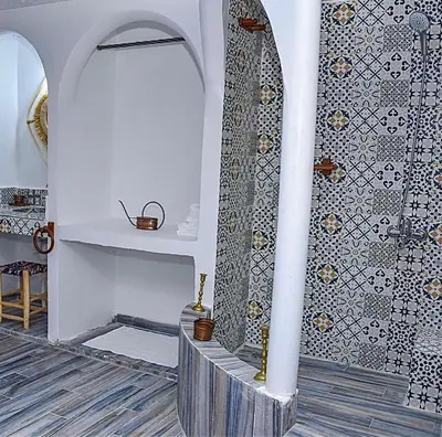 a bathroom with a shower and a tile wall at Tynass Ferme - Fes in Fès