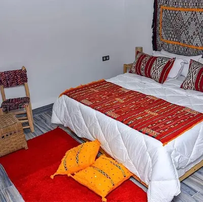 a bedroom with a bed with a red rug and a chair at Ferme Tynass - Amazigh Room Fes