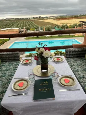 a table with plates and flowers on it with a pool at Ferme Tynass - Amazigh Room Fes