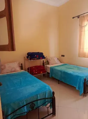 a bedroom with two beds and a suitcase in it at Dar Bedda in Merzouga