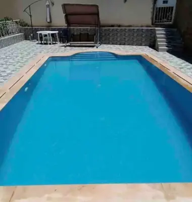 a large blue swimming pool with a table and a chair at Villa avec Piscine Meknes in Meknès