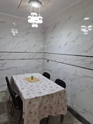 a dining room with a table and chairs and white marble walls at Villa avec Piscine Meknes in Meknès