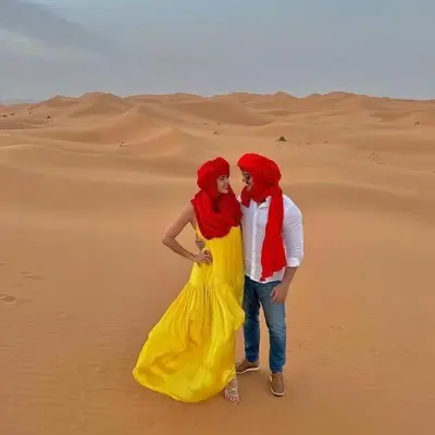 a man and woman standing in the desert at Golden Silence Camp in Merzouga