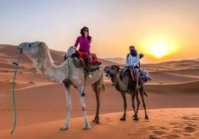 two people riding on the camel in the desert at Merzouga Luxury Camp in Merzouga