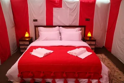 a red and white bed with two white towels on it at Top Desert Camp in Merzouga