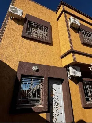 a yellow building with two windows and a door at merzouga apartment in Merzouga