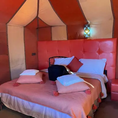 a bed in a room with a red head board at Luxury camp in Merzouga