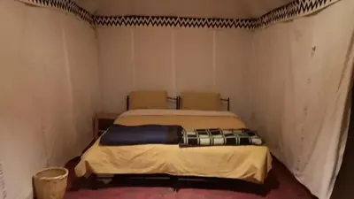 a bedroom with a bed in a room with two chairs at Colorado Desert Camp in El Gouera