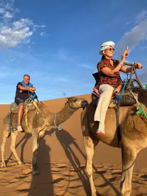 two people riding on a camel in the desert at Colorado Desert Camp in El Gouera