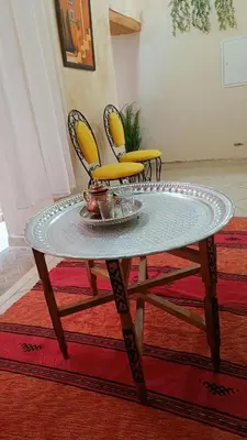 a glass table with two yellow chairs on a rug at chez dar Ayoub in Fès
